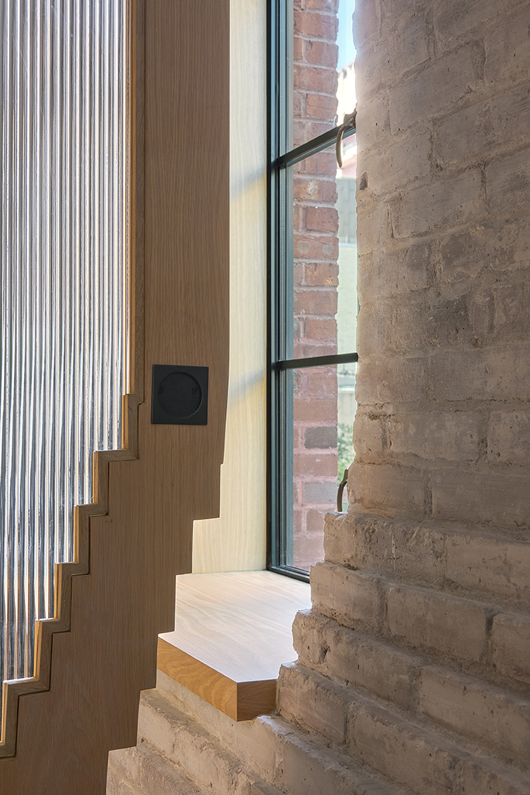 Stepped wood door frame interlocking with existing brick wall